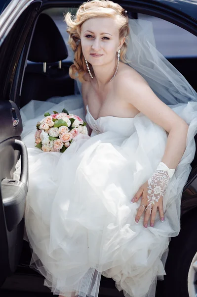 Portret van een mooie bruid in een auto. Close-up portret van een vrij verlegen bruid in een auto-venster. — Stockfoto