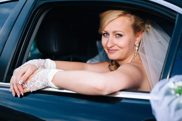 Retrato de uma noiva bonita num carro. close-up retrato de uma noiva muito tímida em uma janela do carro . — Fotografia de Stock