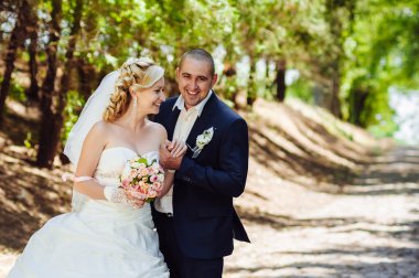 Açık havada bahar doğa üzerinde yürüme gün düğününde gelin ile damat. Gelin çift, mutlu yeni evli kadın ve yeşil park kucaklayan adam.