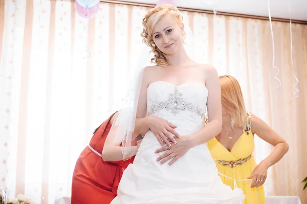 Bridesmaid is helping the bride to dress. — Stock Photo, Image