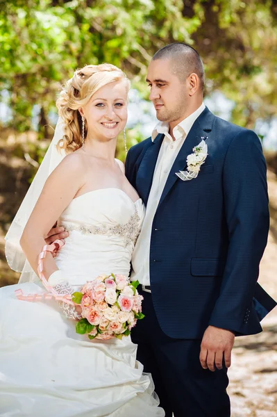 Mariée avec marié le jour du mariage Promenade en plein air sur la nature printanière. Couple nuptial, Bonne femme nouvellement mariée et l'homme embrassant dans le parc vert . — Photo