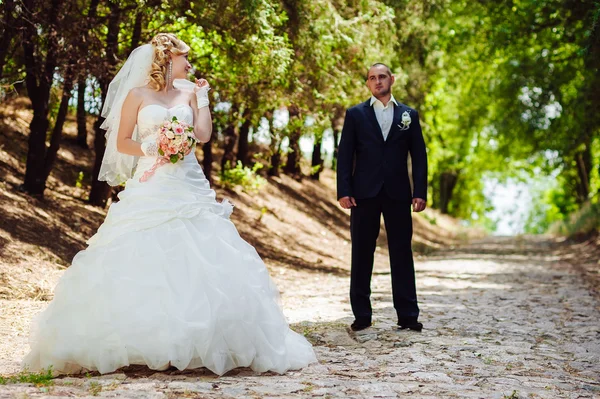 Νύφη με γαμπρός στο γάμο ημέρα περπάτημα σε εξωτερικούς χώρους στη φύση την άνοιξη. Νυφικό ζευγάρι, γυναίκα ευτυχισμένη νεόνυμφο και άνδρας αγκαλιάζει στο καταπράσινο πάρκο. — Φωτογραφία Αρχείου