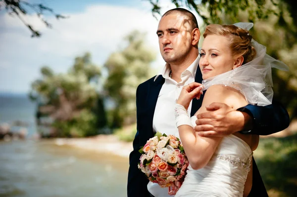 Braut und Bräutigam am Hochzeitstag beim Spazierengehen in der Natur des Frühlings. Brautpaar, glückliche frisch vermählte Frau und Mann umarmen sich im grünen Park. — Stockfoto