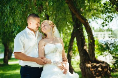 Açık havada bahar doğa üzerinde yürüme gün düğününde gelin ile damat. Gelin çift, mutlu yeni evli kadın ve yeşil park kucaklayan adam.