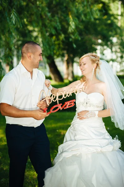 Nevěsta s ženichem na svatební den chůze venku na jarní přírody. Novomanželé, Happy novomanželský žena a muž objímal v parku. — Stock fotografie