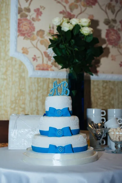 Весільний торт в біло-блакитній комбінації, прикрашений квітами, стрічками . — стокове фото
