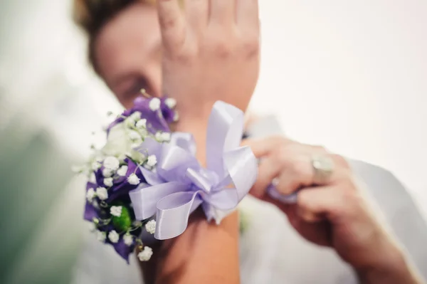 Brudar hand sätta boutonniere blomman på brudgummen — Stockfoto