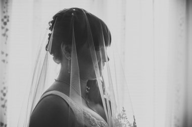 Genç güzel gelin damat pencerenin yanında bekler. Büyük pencere bekleyen yanında duran güzel genç kadın