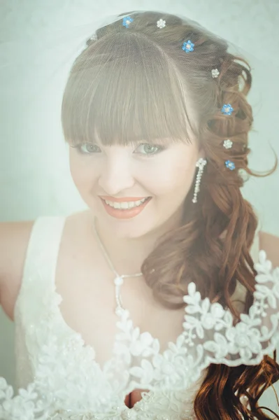 Young beautiful bride waits for groom near the window. Beautiful  young woman standing beside a large window waiting — Stock Photo, Image