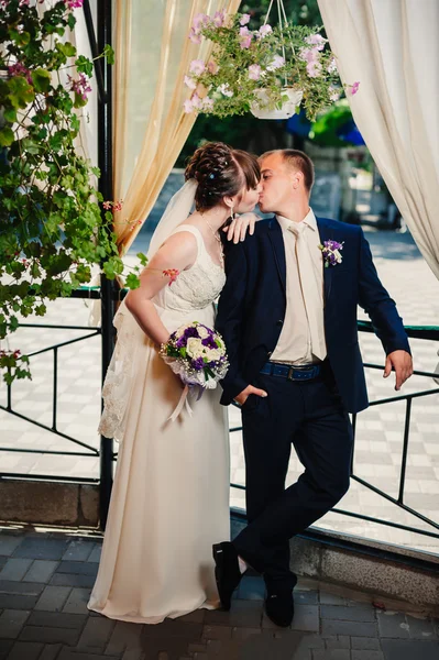Fiatal menyasszony és a vőlegény a parkban, menyasszonyi csokor, esküvői ruhák — Stock Fotó