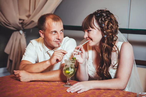 Charmiga bruden och brudgummen dricka mojito på deras bröllop fest på en lyxig restaurang. — Stockfoto