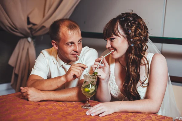 Encantadores novios beben mojito en su celebración de boda en un lujoso restaurante . —  Fotos de Stock