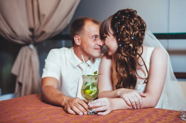 魅力的な花嫁と花婿は、豪華なレストランでの結婚式のお祝いにモヒートを飲む. — ストック写真