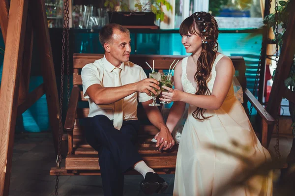 Felice sposa e sposo bere mojito, oscillando su un'altalena — Foto Stock