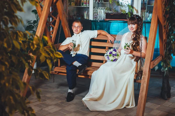 Heureux mariée et marié boire mojito, balançant sur une balançoire — Photo