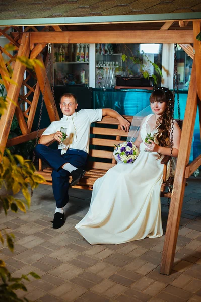 Happy bride and groom swinging on a swing — Stock Photo, Image