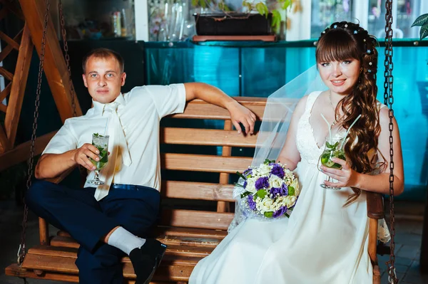 Happy bride and groom swinging on a swing — Stock Photo, Image