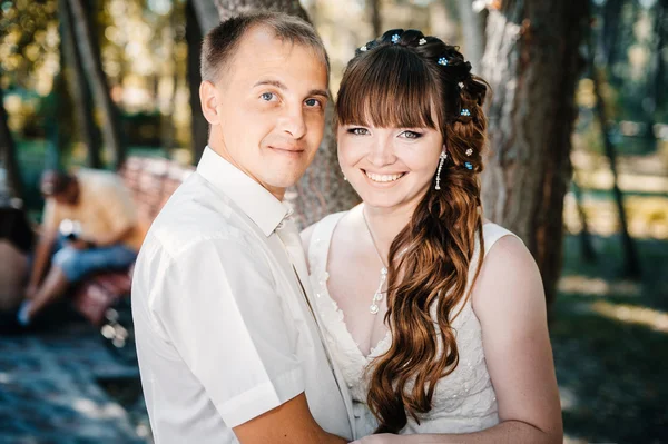 Pareja de boda besándose en verde parque de verano. novia y novio besándose, de pie juntos al aire libre, abrazándose entre árboles verdes. Novia celebración de la boda ramo de flores — Foto de Stock