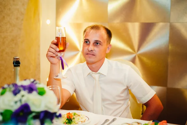 Junger Bräutigam im Restaurant sitzt am Banketttisch — Stockfoto