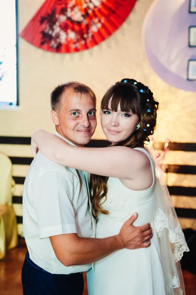 Wedding dance of young bride and groom in banqueting hall. Kiss, embrace — Stock Photo, Image