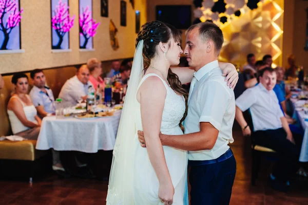 Wedding dance of young bride and groom in banqueting hall. Kiss, embrace — Stock Photo, Image