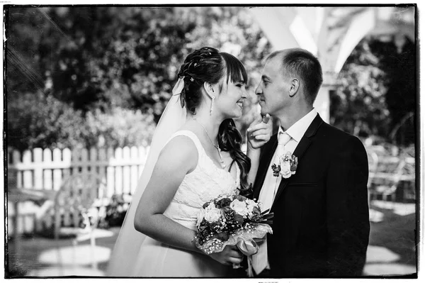 Matrimonio coppia baciarsi nel verde parco estivo. sposa e sposo baciarsi, stare insieme all'aperto, abbracciarsi tra alberi verdi. Sposa tenuta bouquet da sposa di fiori — Foto Stock