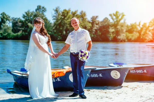 A wedding by the sea. Honeymoon. The bride and groom hugging on the shore of Lake. groom and bride hugging on a green lake. Groom and Bride in a park. wedding dress. Bridal wedding bouquet of flowers — Stock Photo, Image