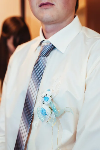 Main de mariée mettant la fleur boutonnière sur un marié — Photo