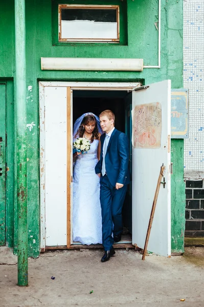 Happy bride and groom posing by the old house — Stock Photo, Image