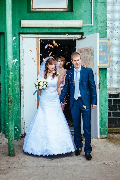 Happy bride and groom posing by the old house — Stock Photo, Image