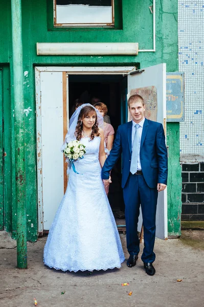 Lyckliga bruden och brudgummen poserar av det gamla huset — Stockfoto