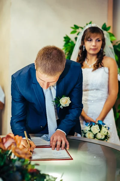 Jong koppel bruiloft documenten ondertekenen. — Stockfoto