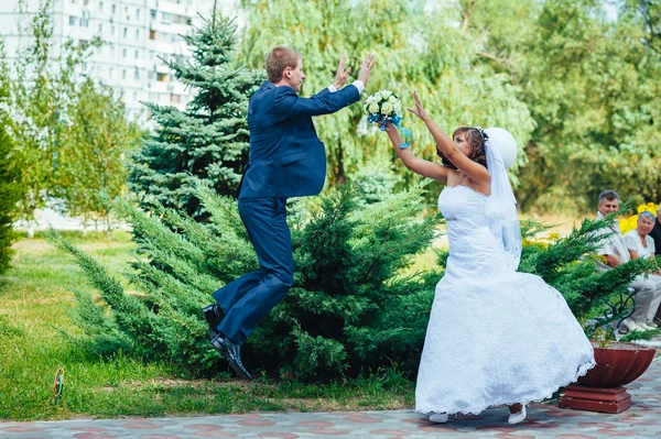 Bride and groom jumping in the air — Stock Photo, Image