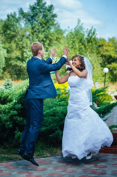 Bride and groom jumping in the air — Stock Photo, Image