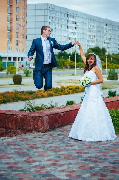 Bride and groom jumping in the air — Stock Photo, Image