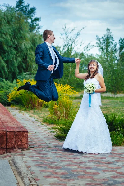 Nevěsta a ženich skákání ve vzduchu — Stock fotografie