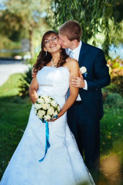 Gelin ve damat gün açık havada yürüyüş düğününde Doğa bahar. Gelin çift, mutlu yeni evli çift yeşil park kucaklayan.