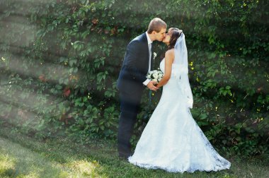 Gelin ve damat gün açık havada yürüyüş düğününde Doğa bahar. Gelin çift, mutlu yeni evli çift yeşil park kucaklayan.