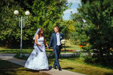 Gelin ve damat gün açık havada yürüyüş düğününde Doğa bahar. Gelin çift, mutlu yeni evli çift yeşil park kucaklayan.