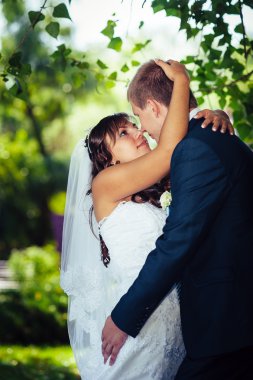 Gelin ve damat gün açık havada yürüyüş düğününde Doğa bahar. Gelin çift, mutlu yeni evli çift yeşil park kucaklayan.
