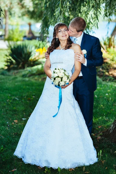 Novia y novio en el día de la boda caminando al aire libre en la naturaleza de primavera. Pareja nupcial, feliz pareja recién casada abrazándose en el parque verde . —  Fotos de Stock