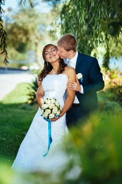 Novia y novio en el día de la boda caminando al aire libre en la naturaleza de primavera. Pareja nupcial, feliz pareja recién casada abrazándose en el parque verde . — Foto de Stock