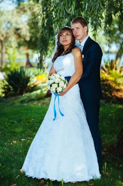 Nevěsty a ženicha na svatební den chůze venku na jarní přírody. Svatební pár, Happy novomanželský pár objímat v parku. — Stock fotografie