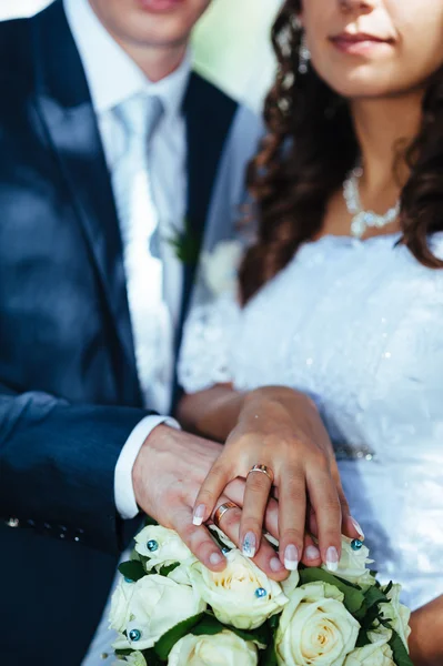 Mãos da noiva e noivo com anéis em um belo buquê de casamento — Fotografia de Stock