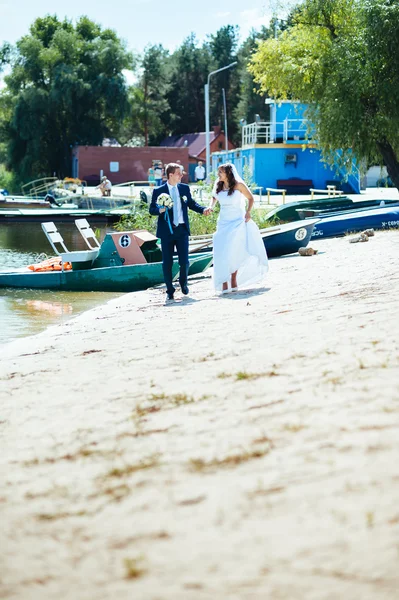 Loving wedding couple standing and kissing near water — Stock Photo, Image