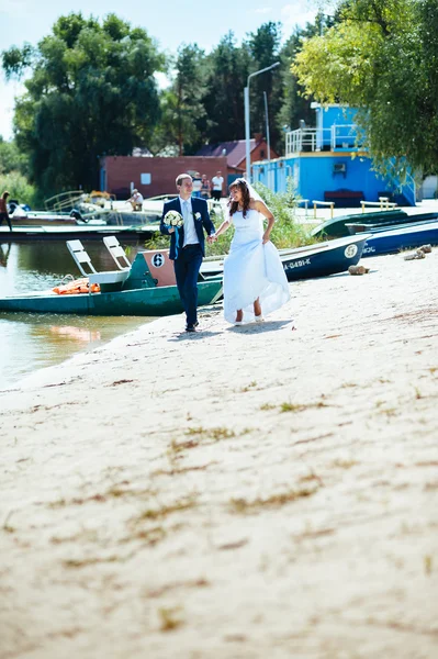 Loving wedding couple standing and kissing near water — Stock Photo, Image
