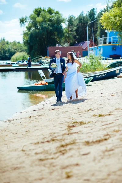 Loving wedding couple standing and kissing near water — Stock Photo, Image