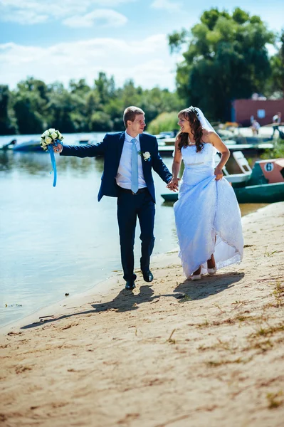 Liefdevolle bruidspaar permanent en kussen in de buurt van water — Stockfoto