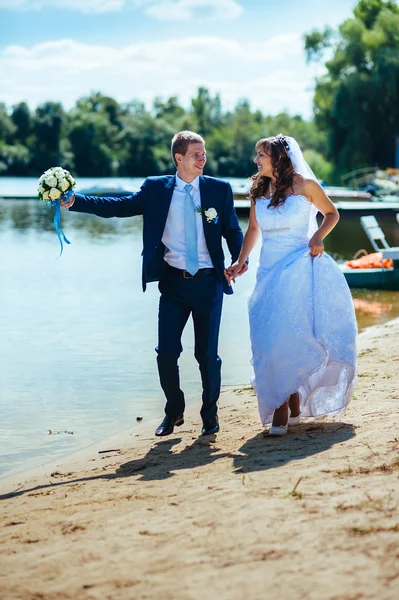 Liefdevolle bruidspaar permanent en kussen in de buurt van water — Stockfoto