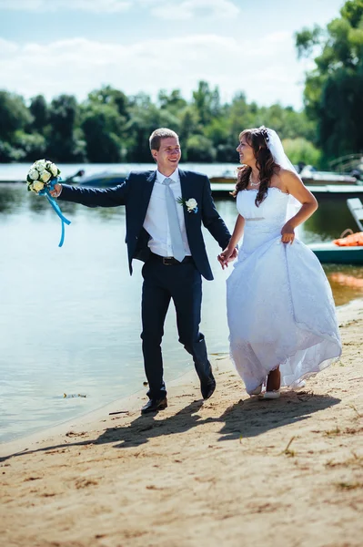 Loving wedding couple standing and kissing near water — Stock Photo, Image